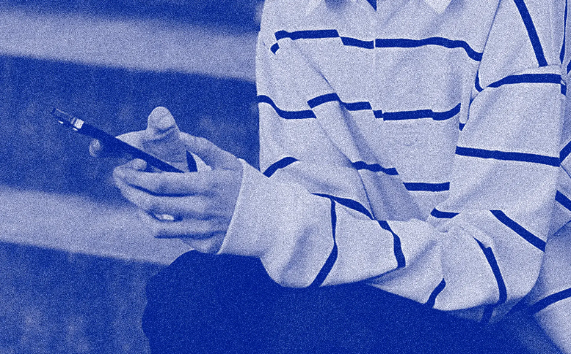 A person in a striped jumper holding a phone, tinted blue